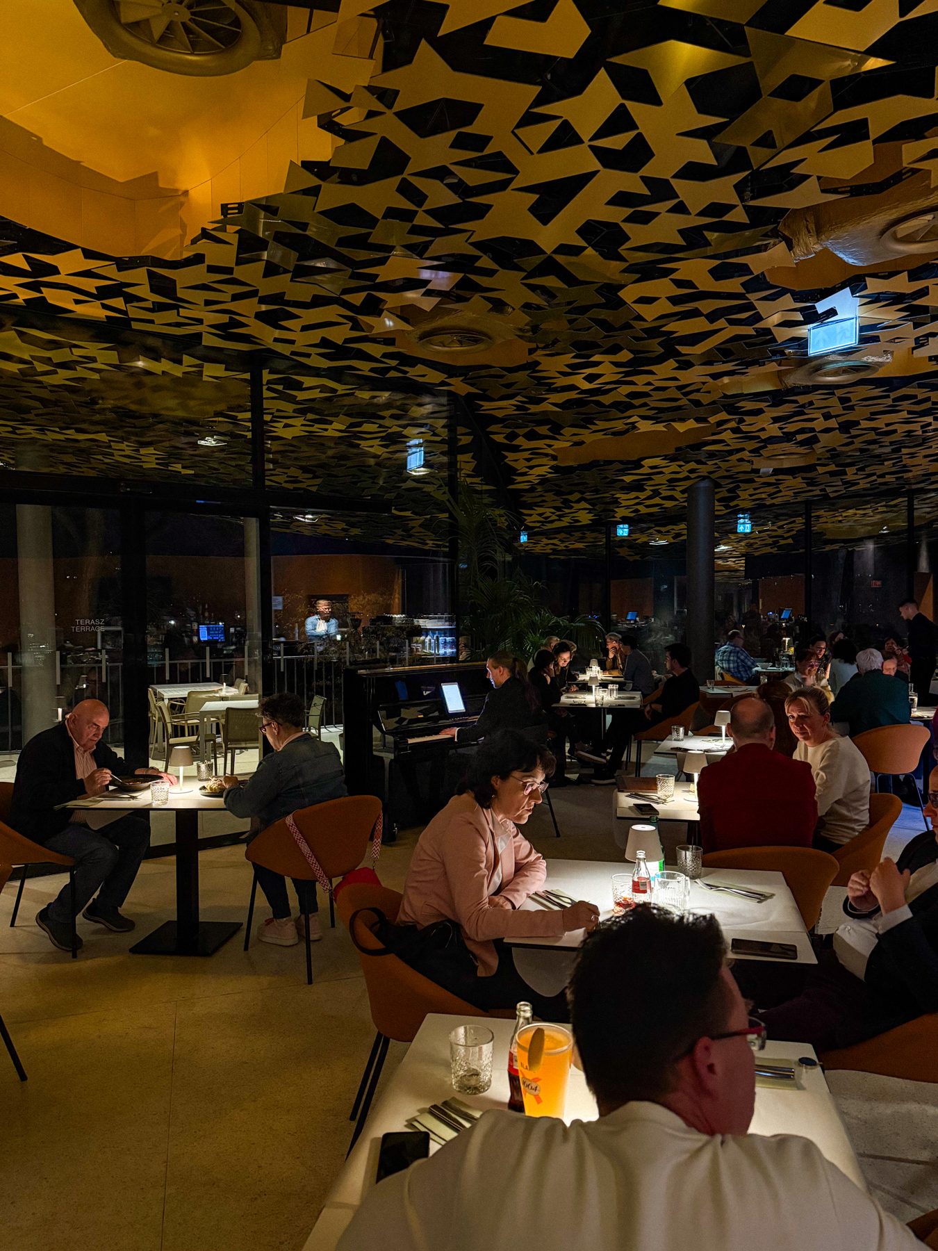 A pianist playing for diners in a restaurant under a gold patterned ceiling